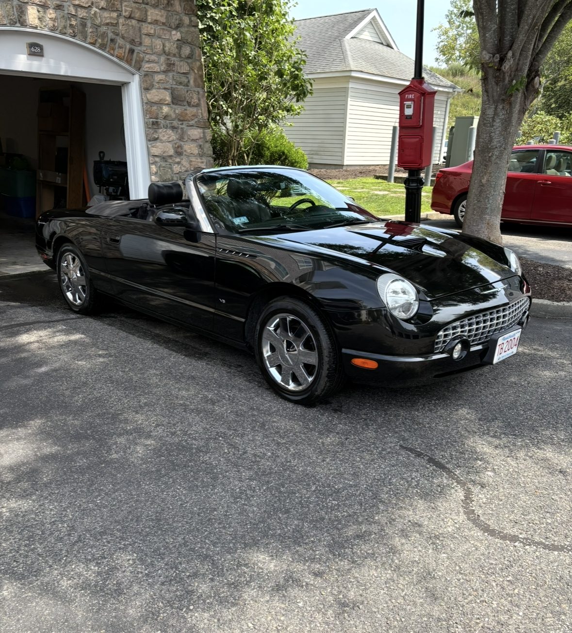 Black Ford Thunderbird retro convertible with the top down and chrome wheels, detailed and parked on a driveway