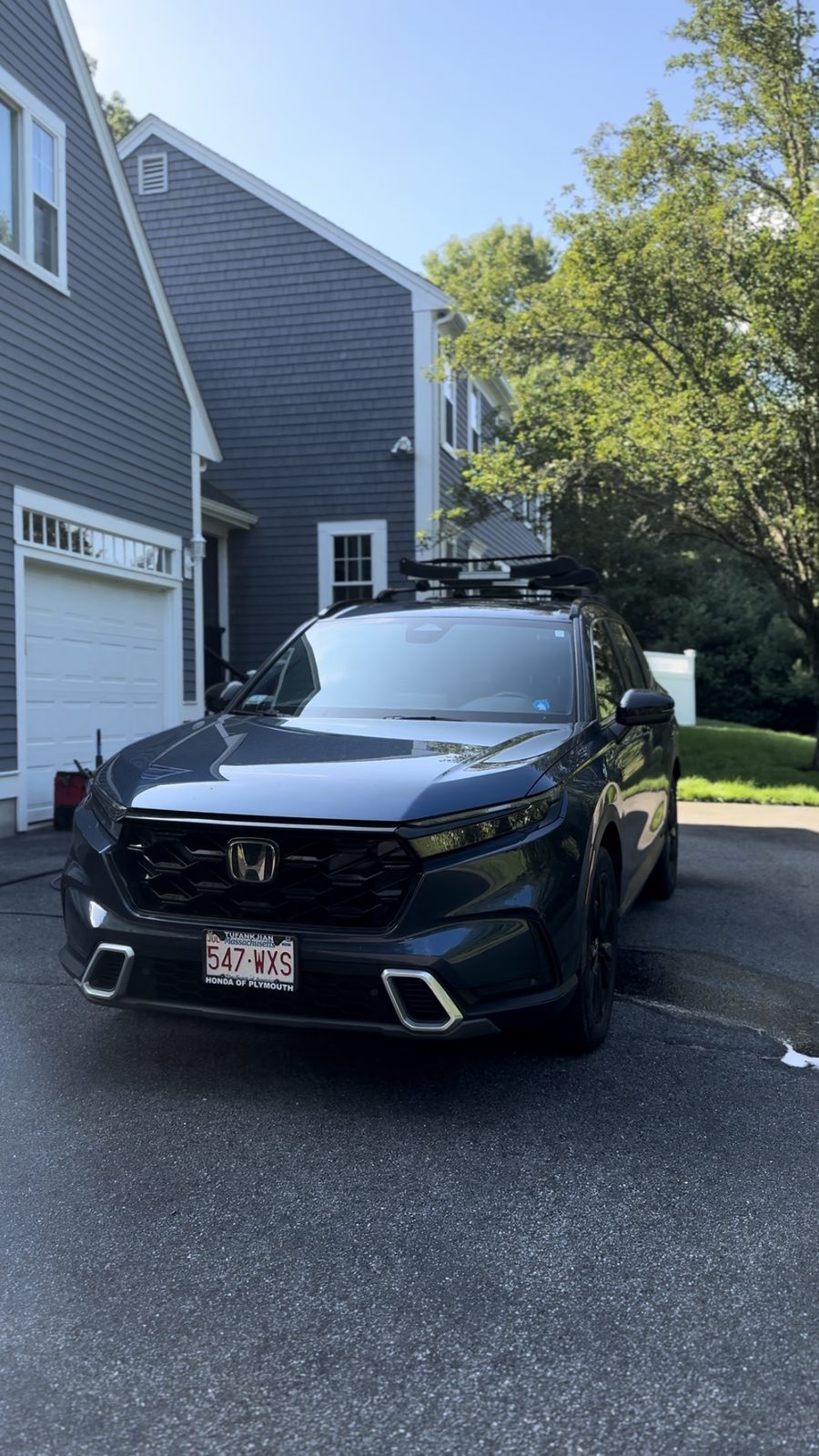 Dark Honda CR-V Sport Touring hybrid parked in a driveway after detailing, hood and flanks reflecting the sky